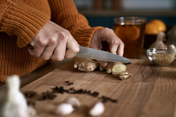 Close up of caucasian woman cutting ginger in kitchen