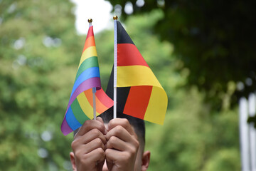 Rainbow flag and Germany national flag holding in hand, soft and selective focus, concept for...