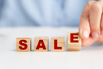 Businesswoman placing wooden blocks on the white table, "SALE" concept.