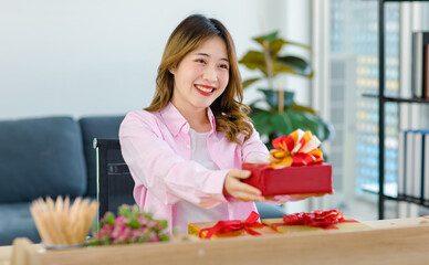 Millennial Asian young happy cheerful female teenager sitting smiling on chair in living room at...