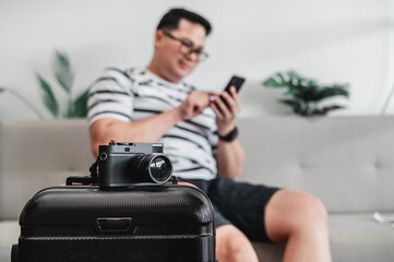 Close-up of Retro camera on luggage with traveler man sitting on sofa background