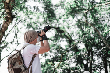 Asian traveler man with backpack taking a photo in the park