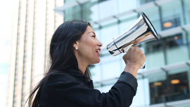 Latin business woman speaking into a megaphone in a business zone.