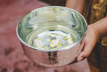 Female hands holding water bowl on Songkran festival