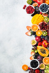 Healthy raw rainbow fruits background, mango papaya strawberries oranges passion fruits berries on oval serving plate on light kitchen top, top view, copy space, selective focus