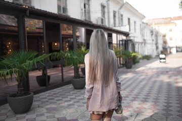 Fototapeta na wymiar Beautiful lady with long smooth hair dressed fashion batforts, dress in heart and jacket walking in the street of the city.