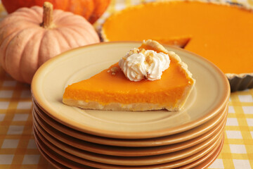 Stacked plates with piece of fresh homemade pumpkin pie with whipped cream on table