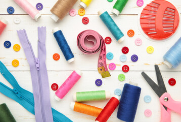 Sewing supplies on white background: sewing thread, scissors, a large spool of thread, pieces of cloth, needles,centimeter, buttons. Vertical photo