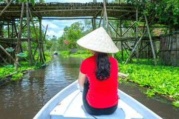 Traveler woman on a boat tour along the canals in the mangrove forest. This is an eco tourism area at Mekong Delta in An Giang, Vietnam
