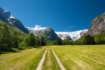 Walking through green fields and forrest along rocky trails to reach the impressive Bergsetbreen glacier in Jostedalsbreen National Park, Norway