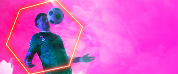 Caucasian male player balancing ball on chest over illuminated hexagon shape against pink background