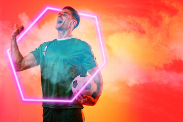 Caucasian male player with soccer ball screaming over illuminated hexagon against neon background