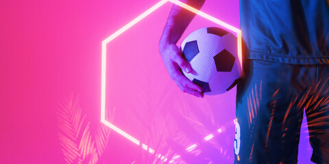 Midsection of caucasian male player holding soccer ball over illuminated hexagon and plants