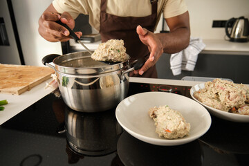 Unrecognizable young black man preparing boiled chicken mince with vegetables recipe in a kitchen.