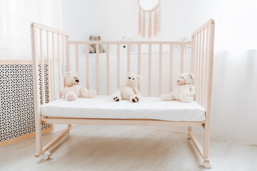 A white bedroom with a baby cot and teddy bears. bright bedroom for a child