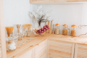 Assortment of cereals and pasta in glass jars and kitchen utensils on a wooden table. Scandinavian-style kitchen. dried garlic.