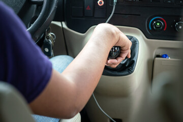 Action of a driver hand is shifting manual transmission (MT) gear during driving a car, photo from behind. Transportation occupation service with people part, selective focus at the gear head part.