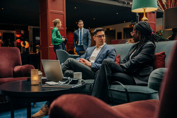 Male and female entrepreneurs discussing business strategy while sitting in hotel lounge