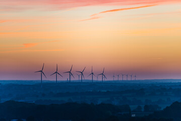 Postcard panorama. View of a wind farm at sunrise. Renewable energies have an impact on the landscape. Place for text.