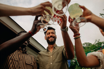 Low angle view of happy multiracial friends toasting drinks at party