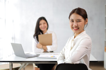 Portrait of happy smiling Asian business woman working with colleagues in the office.