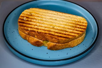 Keuken foto achterwand Closeup of the panini in the blue plate on the gray background © Adrian Vaida/Wirestock Creators