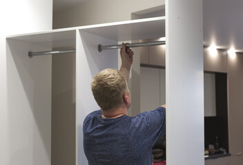A master furniture maker assembles a closet in the hallway, screws the fittings in close-up.  A...
