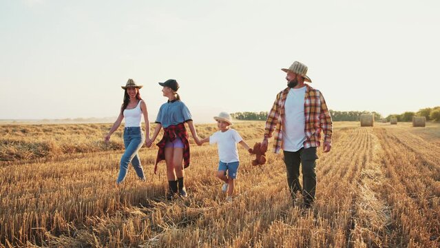 Happy family silhouette walk at sunset. Mom dad and childrens go holding hands in agricultural field. Friendly family and travel together on rural in summer. Father point finger at nature landscape.