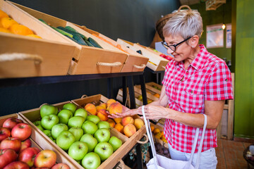 Mature woman buying goods in fruits and vegetables shop.