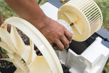 A repairman removes the motor, blower and condenser fan from a window type AC. Air conditioner...