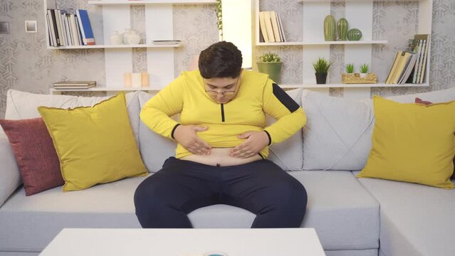Obese overweight boy.
Obese child looking at his belly, unhappy at home.
