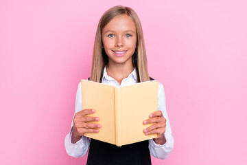 Photo of intelligent schoolkid reading homework novel in classroom isolated on pastel color background