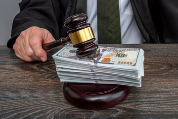 Judge and money concept. Judge's gavel on the table. Law Lord wearing gown using a hammer for verdict, justice judgment at courts of law. Dollars, bill, corruption, cost, finances, expenses, salary