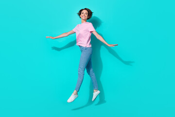 Obraz premium Full size photo of nice pretty cute girl pink t-shirt jeans white sneakers clothes flying jumping isolated on turquoise color background
