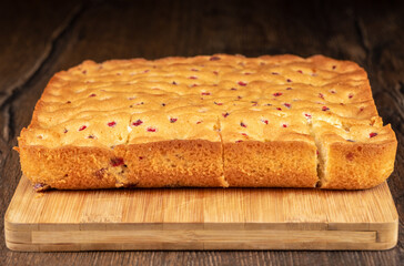 Selective focus on the front of a berry pie cut into pieces on a cutting board.