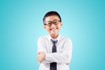 Cheerful schoolboy crossing hands on studio