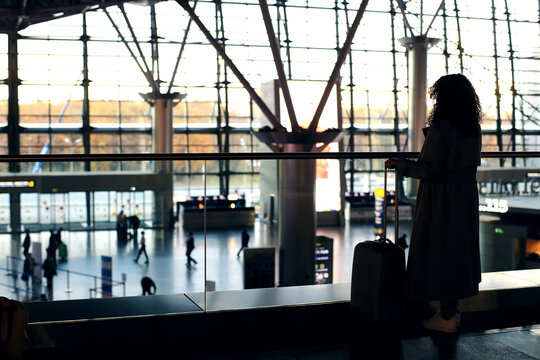 Airport. Beautiful woman with a suitcase at the airport is waiting for her departure. Migration and travel concept.