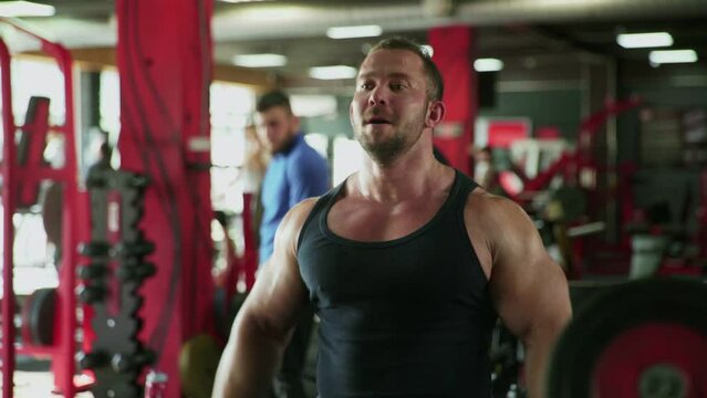An attractive man bodybuilder performing Side raise exercise with dumbbells at gym