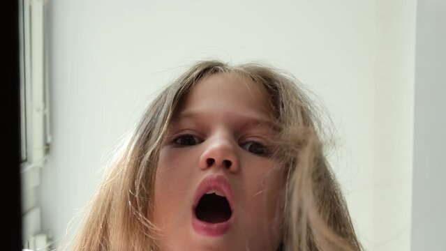 Kid girl looking into gift box, face of surprised and happy child close up. Little girl opening box with surprise and looking inside. Kid received toy delivery from an online store. Slow motion