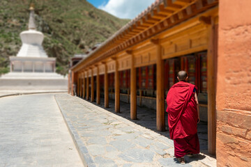 Fototapeta premium Buddhist monk with prayer wheels at Labrang Temple, Xiahe, Gannan, Gansu, China