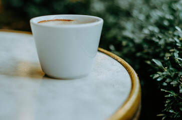 Coffee cup on terrace table close up on a rainy day with Christmas lights reflection
