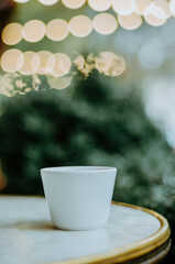 Vertical coffee cup on outdoor terrace table with bokeh Christmas lights