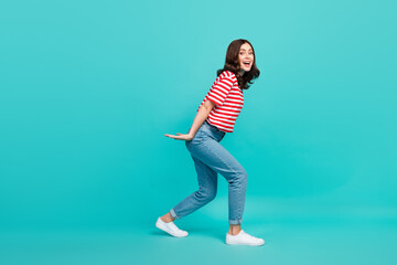 Fototapeta na wymiar Full length photo of positive funky lady arm hold big object empty space dressed striped stylish clothes isolated on cyan color background