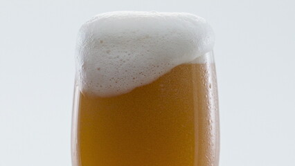 Closeup beer foaming glass in super slow motion. Foam alcohol beverage flowing.