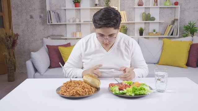 Obese boy pays attention to food.
Obese child who prefers to eat salad instead of pasta.
