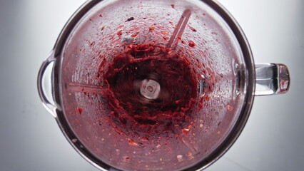 Fresh berry smoothie swirling inside blender in super slow motion close up. 
