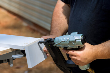 With help of pneumatic air gun carpenter connects assembly for wood boards with nails