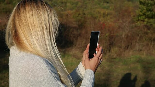 woman taking pictures with her phone in nature