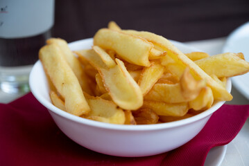 French fries served in a bowl, placed on a table with red napkin 