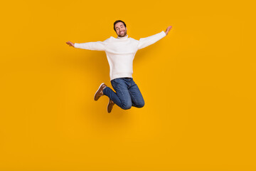 Photo of sweet funky guy dressed white sweater arms sides jumping high isolated yellow color background